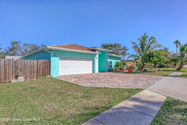 view of side of home featuring fence, stucco siding, an attached garage, and a lawn