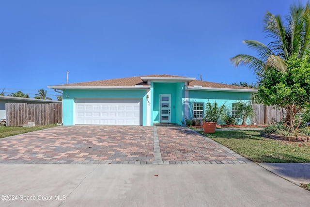 ranch-style house featuring fence, decorative driveway, stucco siding, and an attached garage