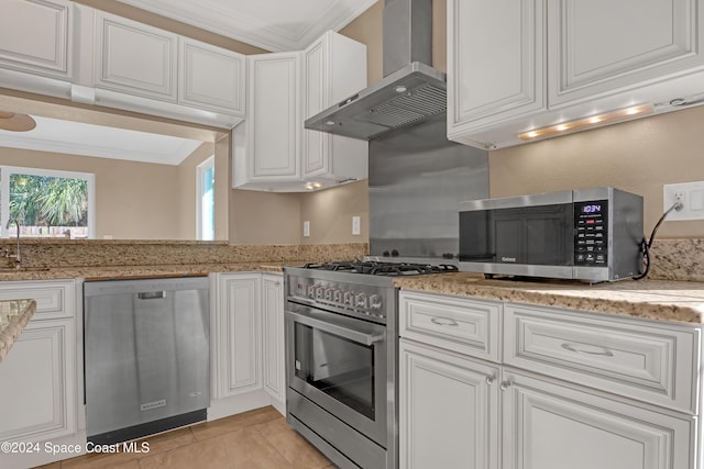 kitchen with wall chimney range hood, crown molding, white cabinets, stainless steel appliances, and light stone countertops