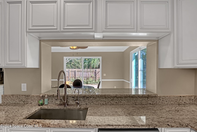 kitchen featuring sink, ceiling fan, white cabinets, light stone counters, and ornamental molding