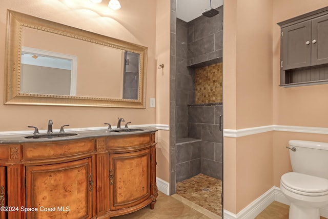 bathroom featuring tiled shower, toilet, and a sink