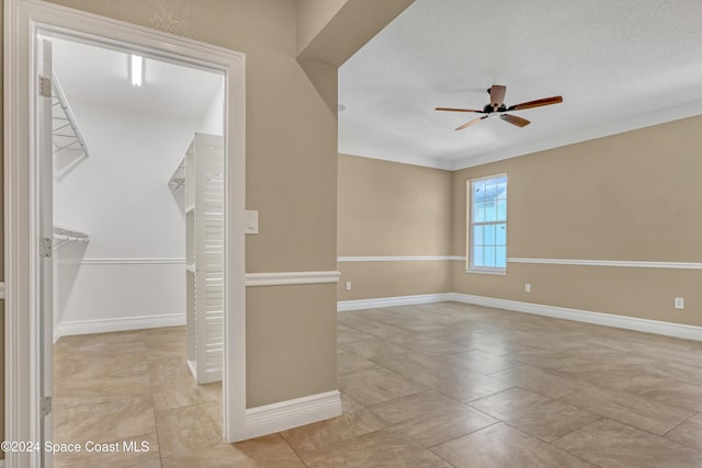 tiled empty room featuring baseboards, a ceiling fan, and a textured ceiling