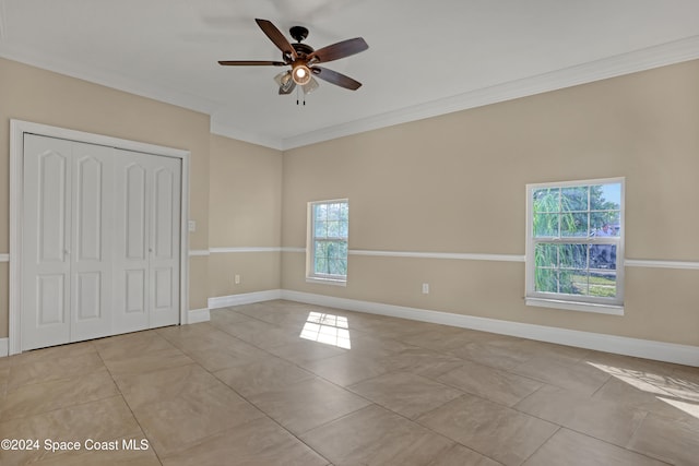 unfurnished bedroom with crown molding, light tile patterned flooring, a closet, and ceiling fan