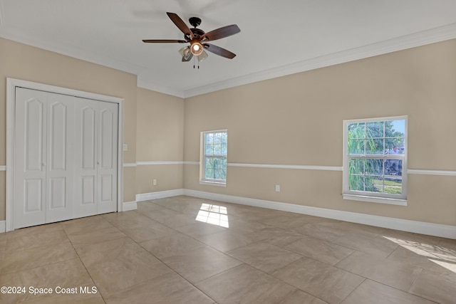 unfurnished bedroom with a closet, ceiling fan, light tile patterned flooring, baseboards, and ornamental molding