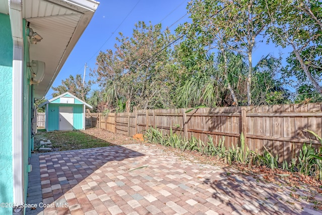 view of patio featuring a storage shed, an outdoor structure, and a fenced backyard