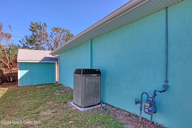 view of property exterior with stucco siding, fence, an outbuilding, a storage shed, and central AC unit