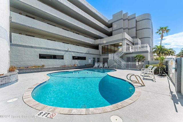 community pool with a patio area and fence