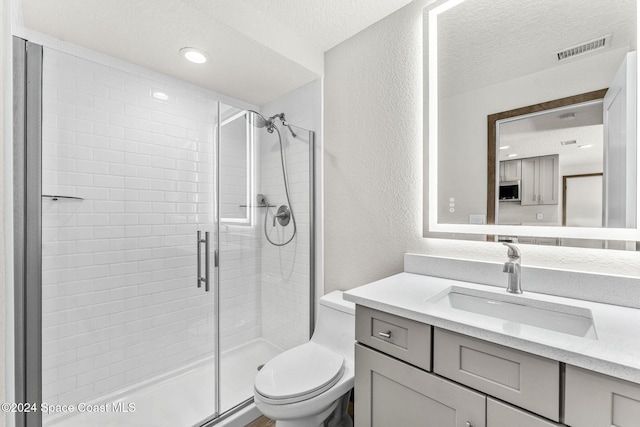 full bath with a shower stall, toilet, a textured ceiling, vanity, and a textured wall
