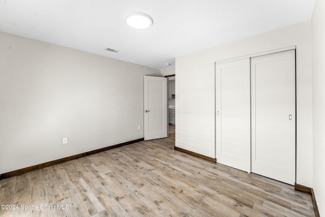 unfurnished bedroom with light wood-style flooring, baseboards, and a closet
