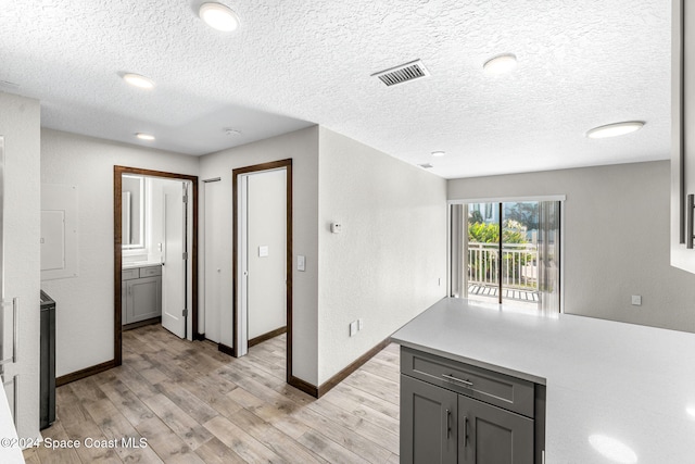 kitchen with gray cabinets, a textured ceiling, and light hardwood / wood-style floors