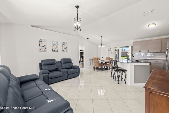 tiled living room with sink, lofted ceiling, and a chandelier