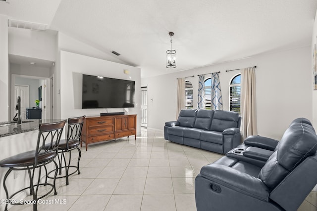 living room featuring light tile patterned floors, a notable chandelier, a textured ceiling, and lofted ceiling