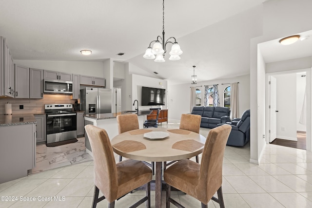 dining space featuring lofted ceiling, sink, and an inviting chandelier