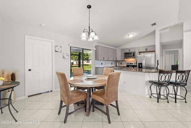 dining space with sink, light tile patterned floors, vaulted ceiling, and an inviting chandelier