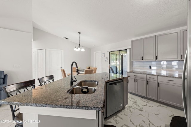 kitchen with sink, dishwasher, vaulted ceiling, decorative light fixtures, and a kitchen island with sink