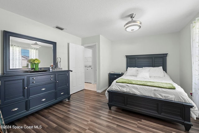 bedroom with washer / clothes dryer, a textured ceiling, and dark wood-type flooring