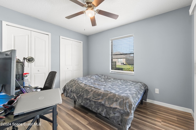 bedroom featuring ceiling fan, multiple closets, a textured ceiling, and dark hardwood / wood-style floors