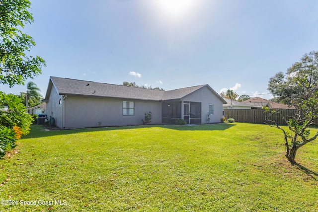 rear view of property featuring a lawn and a sunroom