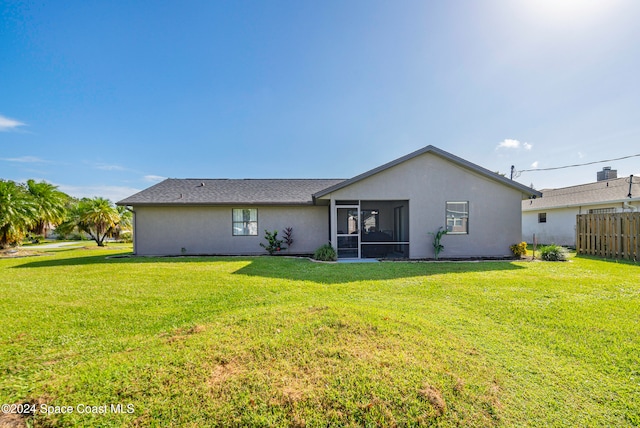 back of property with a sunroom and a lawn