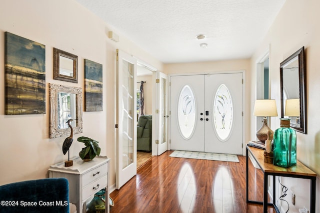 foyer featuring french doors, a textured ceiling, and dark hardwood / wood-style flooring