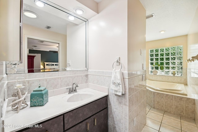 bathroom featuring vanity, tile patterned flooring, and tiled bath