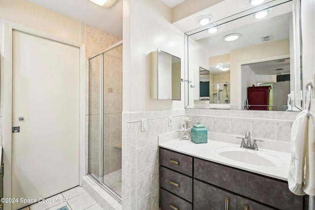 bathroom featuring vanity, tile patterned floors, walk in shower, and tile walls