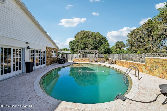 view of swimming pool with french doors and a patio area