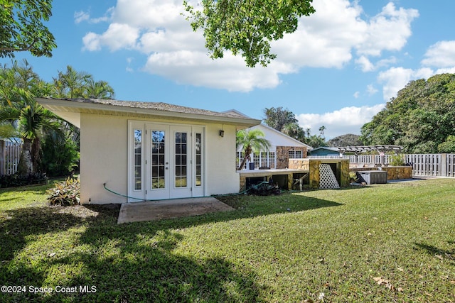 rear view of property featuring a yard, french doors, and a wooden deck