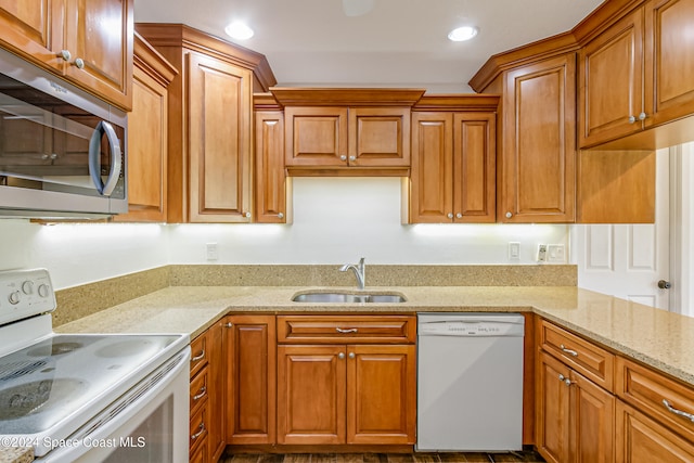 kitchen with sink, light stone countertops, and white appliances