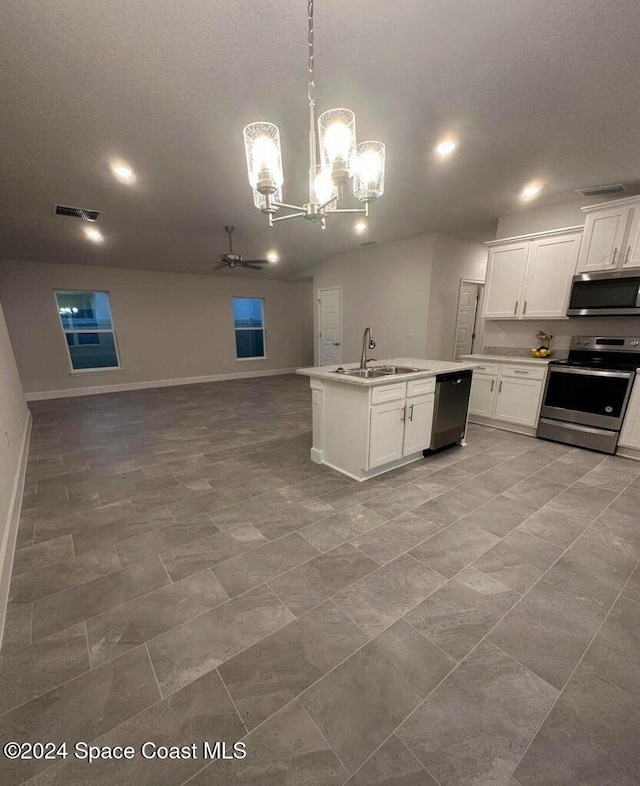 kitchen with stainless steel appliances, sink, pendant lighting, white cabinetry, and ceiling fan with notable chandelier