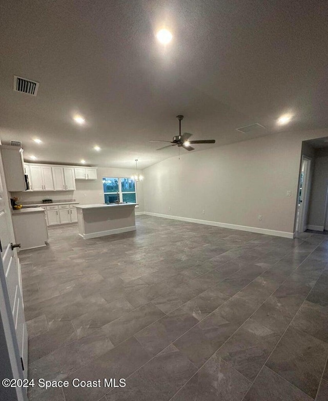 unfurnished living room with a textured ceiling and ceiling fan with notable chandelier