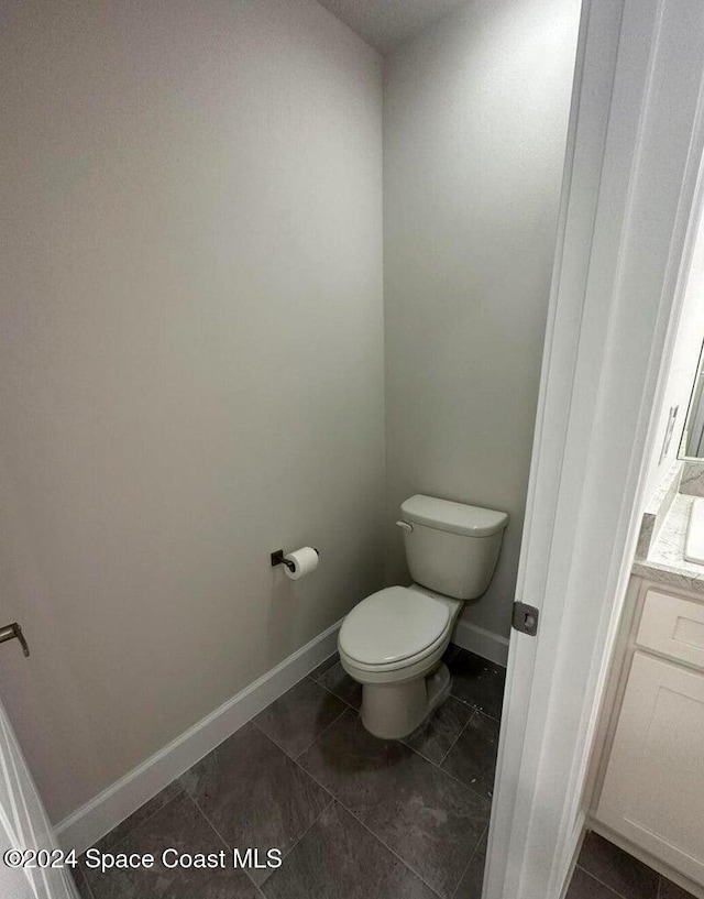 bathroom with toilet, vanity, and tile patterned floors