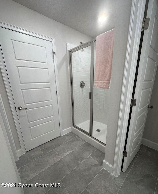 bathroom featuring tile patterned flooring and an enclosed shower