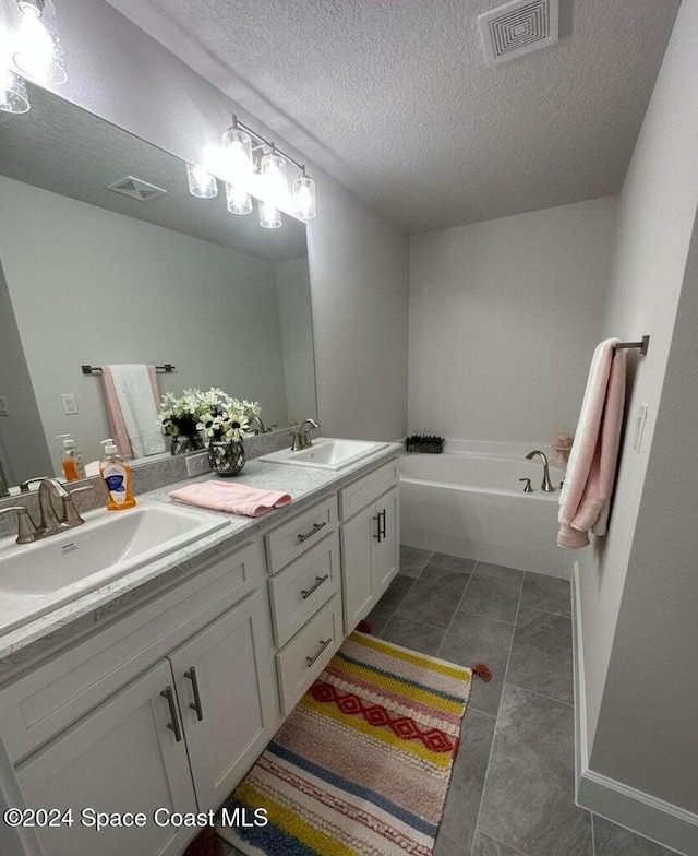 bathroom with vanity, tile patterned floors, a textured ceiling, and a bathing tub