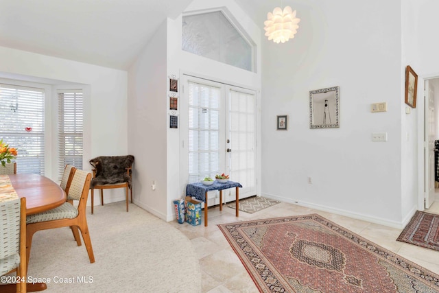 tiled entrance foyer featuring french doors, a notable chandelier, high vaulted ceiling, and plenty of natural light