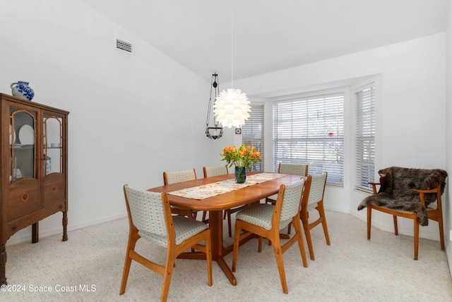 carpeted dining space featuring lofted ceiling