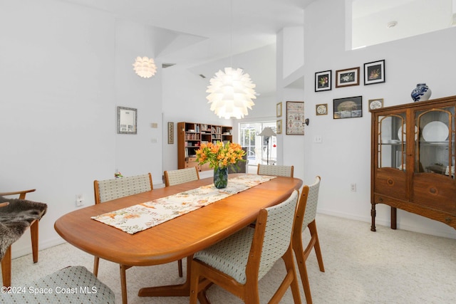 carpeted dining space with high vaulted ceiling