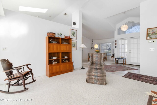 living room featuring french doors, light colored carpet, high vaulted ceiling, and a skylight