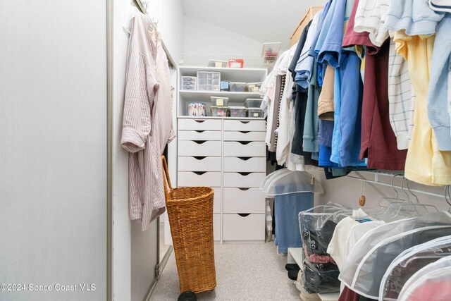 walk in closet featuring light carpet and lofted ceiling