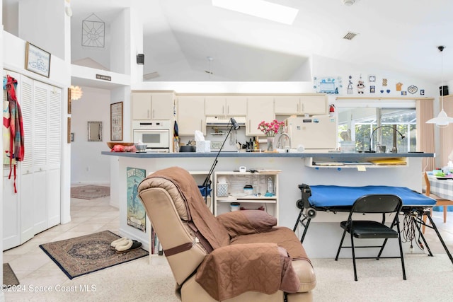 kitchen featuring cream cabinets, light tile patterned floors, vaulted ceiling, sink, and white appliances