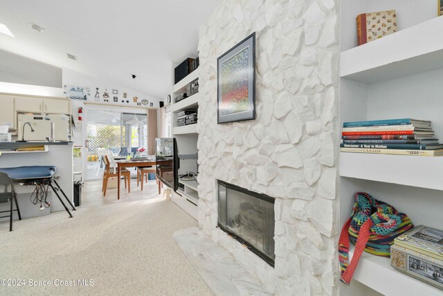 living room featuring a stone fireplace and lofted ceiling