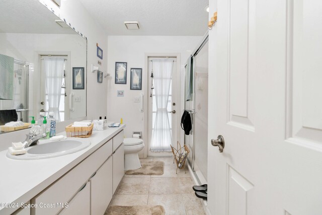 bathroom featuring a shower with door, vanity, toilet, and a wealth of natural light