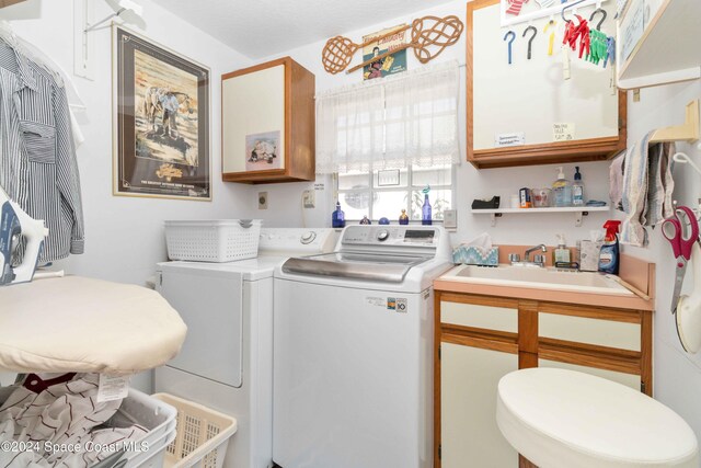 washroom with sink, washer and dryer, and cabinets