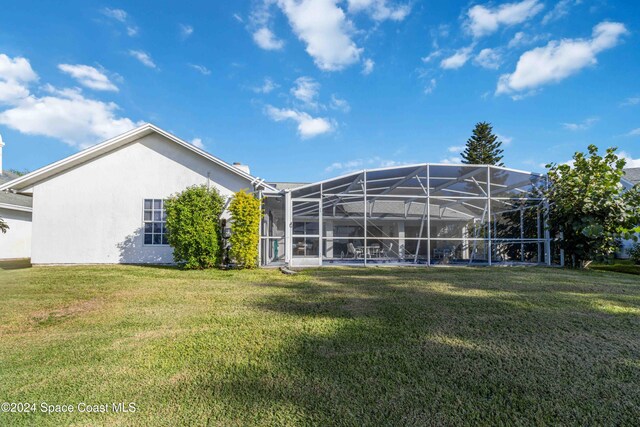 rear view of property featuring glass enclosure and a lawn