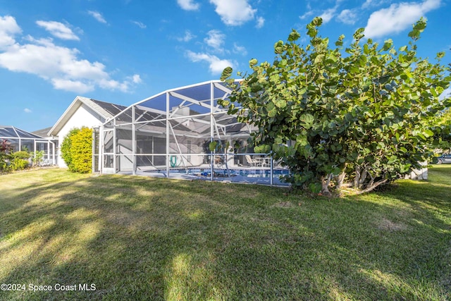 rear view of property featuring a lawn and a lanai