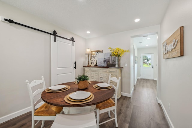 dining area with dark wood-type flooring and a barn door