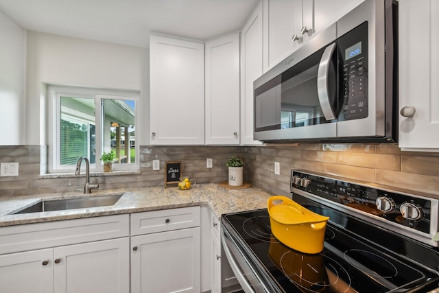 kitchen with decorative backsplash, white cabinetry, sink, and electric range oven