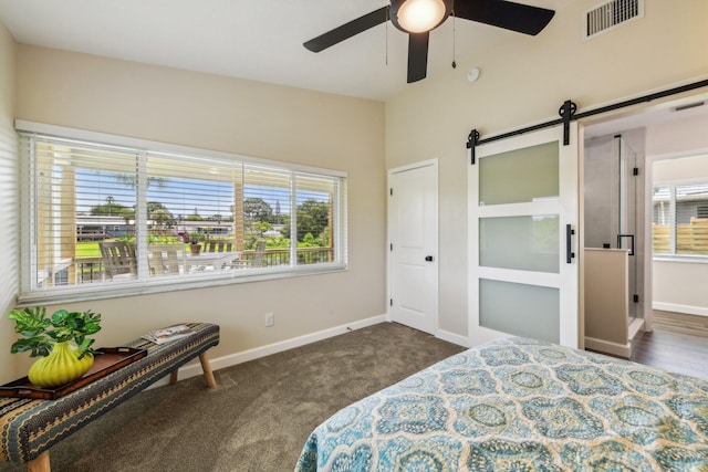 carpeted bedroom with ceiling fan and a barn door