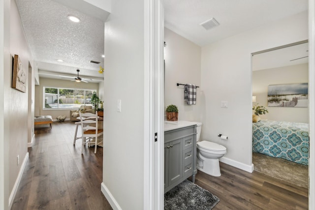 bathroom featuring wood-type flooring, a textured ceiling, toilet, ceiling fan, and vanity