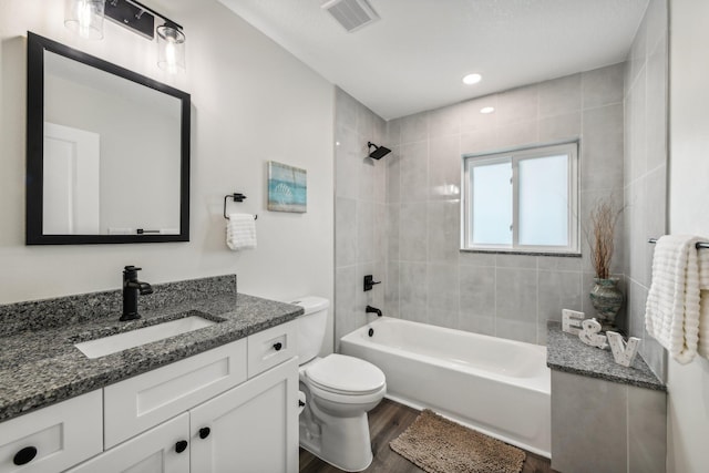 full bathroom with vanity, tiled shower / bath combo, hardwood / wood-style flooring, and toilet